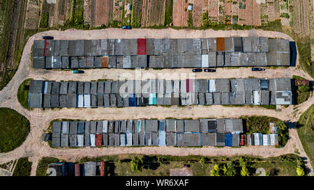 Vista aerea del appartamento garage con piena di parcheggio coperto, le automobili e i verdi alberi di multi-piano edificio residenziale di prima mattina. Infrast urbana Foto Stock