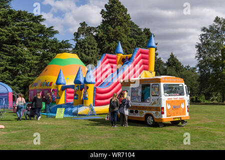 Estate nel parco, un colorato castello gonfiabile con un gelato van davanti; Delapre Abbey, Northampton, Regno Unito Foto Stock