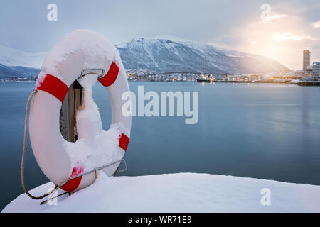 Salvagente coperte di neve sulla riva del famoso Ponte di Tromso attraverso lo stretto di Tromsoysundet, nel nord della Norvegia Foto Stock