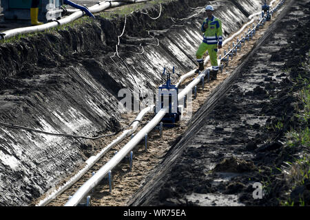 Il 10 settembre 2019, Schleswig-Holstein, Büsum: un lavoratore edile sovrintende al tiro di una corrente diretta cavo di messa a terra. Costruzione della NordLink linea di potenza vicino a Büsum è di continuare. La pipeline, che avrà un costo di circa due miliardi di euro servirà a scambiare le energie rinnovabili tra la Germania e la Norvegia Foto: Carsten Rehder/dpa Foto Stock