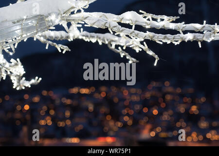 Inverno albero con luci e decorazioni con il defocalizzata luci della città di Tromso città in background, nel nord della Norvegia Foto Stock