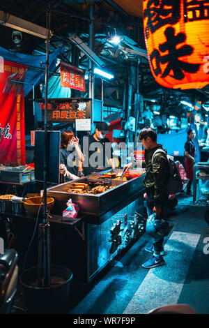 Taichung, Taiwan: il ragazzo è un acquisto di un night snack in un cibo di strada in stallo il mercato notturno in Taichung. Foto Stock