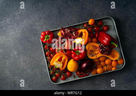 Flatlay con fresche verdure colorate disposte sul vassoio metallico sul cemento grigio Sfondo. Set di ingredienti vegetariani concetto. Copia dello spazio. Foto Stock