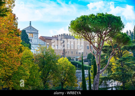 Abbazia di San Miniato al Monte basilica sulla cima della collina di Firenze, Italia. Autunno alberi e pini circostanti Foto Stock