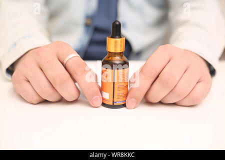 Immagine dell uomo medicina goccia bottiglia tenendo in mano. Isolato su sfondo bianco. Foto Stock