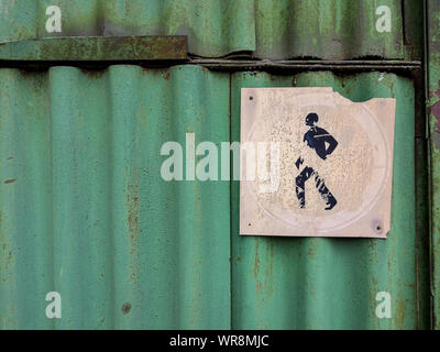 Un vecchio sbiadito passaggio pedonale Simbolo divieto si trova su un vecchio arrugginito verde foglio ondulato di ferro. Stile grunge Foto Stock