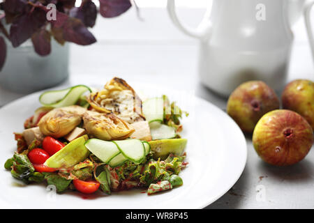 Una squisita insalata con fichi, Carciofo, cetriolo, pomodoro, formaggio feta di agnello di foglie di lattuga condito con salsa di lamponi. Foto Stock