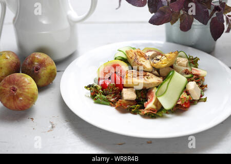 Integratore con insalata di fichi, Carciofo, cetriolo, pomodoro ciliegino, feta su foglie di rucola versata con salsa di lamponi. Foto Stock