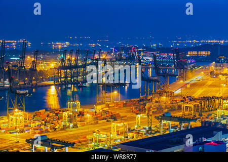 La logistica e il trasporto del contenitore nave da carico con gru di lavoro ponte in cantiere Twilight time. Foto Stock