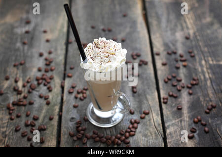 Caffè ghiacciato, bicchiere di caffè con latte, panna e ghiaccio su un sfondo di legno. Foto Stock