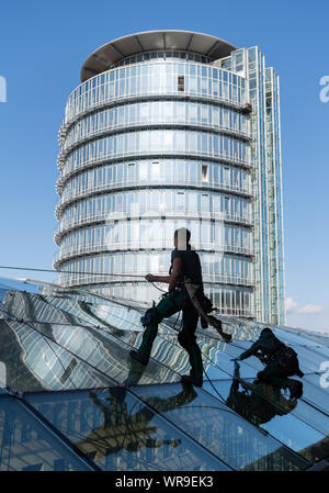 Dresden, Germania. Decimo Sep, 2019. Vetro specializzati e la costruzione di pulitori dalla società di Dresda Purel pulire il tetto di vetro del World Trade Center (WTC) ad una altezza di 27 metri. La curva del tetto di vetro ha una superficie di circa 2700 metri quadrati. Credito: Robert Michael/dpa-Zentralbild/dpa/Alamy Live News Foto Stock