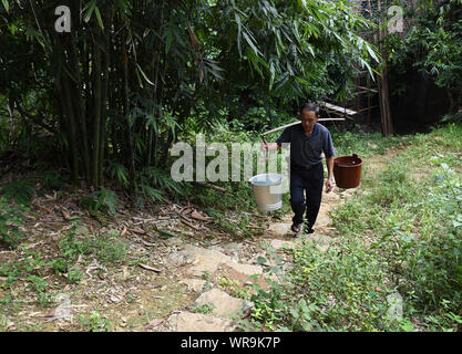 (190910) -- NANNING, Sett. 10, 2019 (Xinhua) -- Professore Huang Mingliao porta acqua per rendere il pranzo per gli studenti a Longpo punto di insegnamento in Aile villaggio, città Jinjie, Tiandeng County, a sud della Cina di Guangxi Zhuang Regione autonoma, Sett. 10, 2015. Dal 2012, reporter ha visitato 250 insegnanti in remote zone di montagna nel Guangxi e registrate le loro vite. Gli insegnanti vi riempire sempre di più ruoli come concierge e cuocere. Ci sono circa 16.74 milioni di insegnanti in Cina, 79% surge dalla figura nel 1985 quando la Cina designato sett. 10 come insegnanti" giorno, il Ministero della Pubblica Istruzione ha detto. Foto Stock