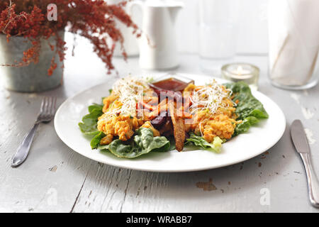 Verdure al forno patata dolce, patata, sedano, carote, barbabietole servita con verdure intingolo su lattuga iceberg. Foto Stock