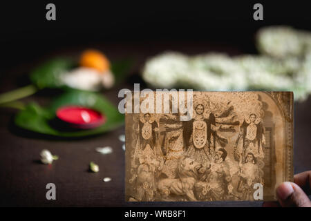 Durga Puja o Pooja immagine di sfondo con copia spazio. Un vecchio vintage fotografia della dea indiana Durga con fiori, kumkum, betel lascia per la r Foto Stock