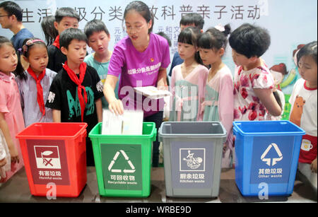 Un Cinese igiene officer insegnare ai ragazzi di ordinare le garbage durante un'immondizia cernita campagna in Suzhou City, est cinese della provincia di Jiangsu, Lug Foto Stock
