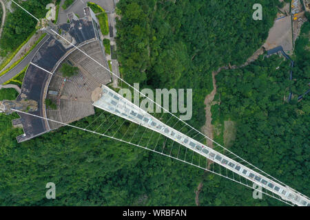 In questa vista aerea, turisti brave la più lunga del mondo e il più alto dal fondo di vetro ponte sopra il Zhangjiajie Grand Canyon a Wulingyuan Scenic e H Foto Stock