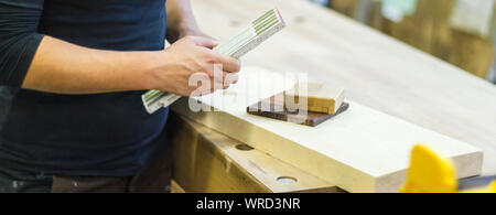 Femmina falegname falegname utilizzando la scala misuratore regola personale e campioni di legno di campioni di materiale in officina Foto Stock