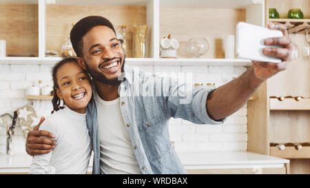 African padre e figlia tenendo selfie su cucina Foto Stock