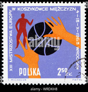 Timbro postale stampato in Polonia che mostra la sfera, le mani e i giocatori, xiii gli uomini europei campionato di pallacanestro di Wroclaw, circa 1963 Foto Stock