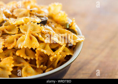 Recipiente di cottura bow tie-in pasta o farfalle di pasta in una fresca pesto, close up