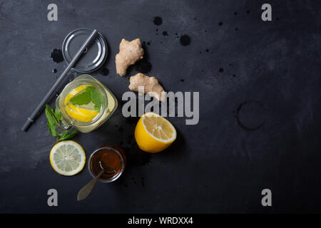 Lo zenzero acqua in un barattolo di vetro con limone e miele su uno sfondo nero con spazio di copia Foto Stock