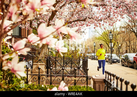 Una donna che corre lungo una strada di città di Boston in primavera. Foto Stock