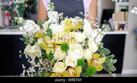 Dimostrazione di composizioni floreali in fiorai studio. Fioraio donna arriva con un bellissimo mazzo di rose e gigli in negozio di fiori. Donna detiene un enorme mazzo nelle sue mani, primo piano. Foto Stock