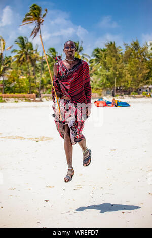 Masai in luminose vestiti nazionali tradizionali di saltare sulla spiaggia Zanzibar Foto Stock