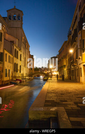 Luce da notte antica Venezia street con il ponte e il campanile di una chiesa Foto Stock