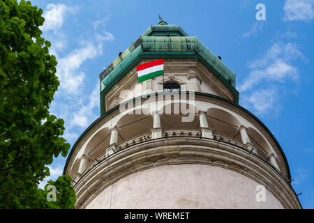 Torre Firewatch Tuztorony in Sopron, Ungheria. Basso angolo di visione in primavera con la bandiera ungherese. Foto Stock