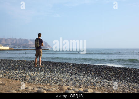 LIMA, Perù - Aprile 2, 2012: Unidentified giovane uomo in piedi sulla rocciosa costa del Pacifico di Miraflores a Lima in Perù Foto Stock