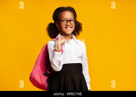 African American Schoolgirl Holding zaino sorridente alla fotocamera, Studio Shot Foto Stock