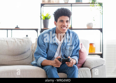 Felice ragazzo adolescente per giocare con i videogiochi di casa utilizzando il joystick Foto Stock