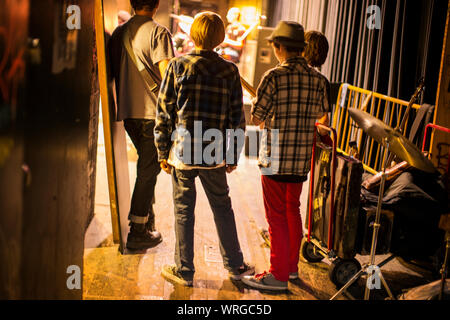 Un gruppo di ragazzi adolescenti la visione di una band che suona sul palco. Foto Stock