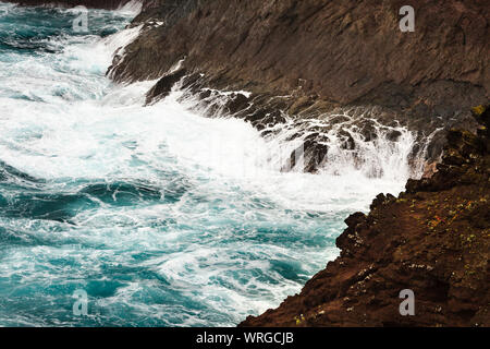 Vista dettagliata di alti spruzzi delle onde di colpire le rocce laviche a Playa de Nogales in La Palma, Spagna. Foto Stock