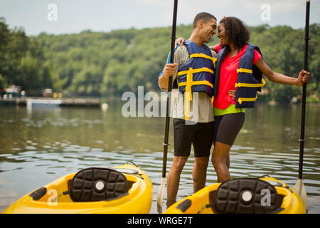 Sorridente coppia giovane abbracciando nella parte anteriore del loro kayak. Foto Stock