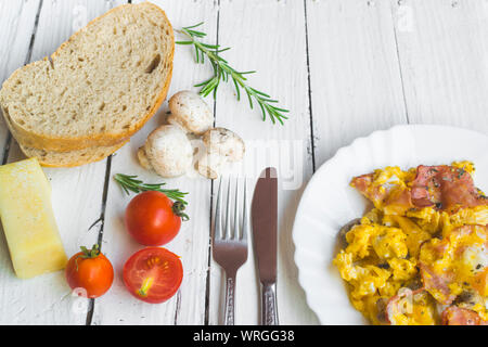 Frittata con pancetta e funghi sul tavolo bianco. Pomodori ciliegini, formaggio e rosmarino come decorazione. Elevato angolo di visione Foto Stock