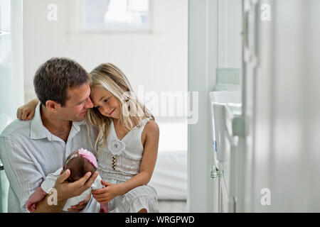 Sorridendo i nuovi genitori orgogliosamente guardare giù al loro neonato figlia. Foto Stock