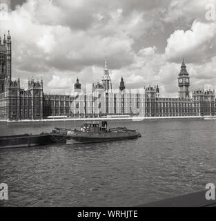 Degli anni Cinquanta, storico, una vista sul fiume Tamigi, mostrando una chiatta su un ormeggio e il Palazzo di Westminster, dove due delle case della funzione del Parlamento europeo, la sede del governo del Regno Unito, Westminster, Londra, Inghilterra, Regno Unito. Foto Stock