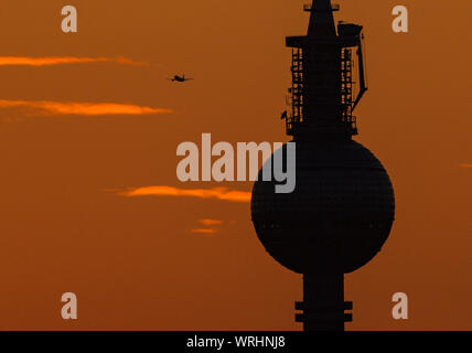 Berlino, Germania. Decimo Sep, 2019. Un aereo vola dietro la torre TV durante il tramonto. Credito: Christophe Gateau/dpa/Alamy Live News Foto Stock
