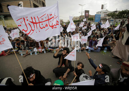 Sanaa, Yemen. Decimo Sep, 2019. I sostenitori dello Yemen's sciita ribelli Houthi, wave bandiere con un Arabo scritta 'disgrace è lontana da noi', che prendono parte a una processione religiosa per contrassegnare il giorno di Ashura, che cade il decimo giorno di Muharram, il primo mese del calendario islamico. Ashura segna il giorno in cui Husayn ibn Ali, il nipote del profeta islamico Maometto, è stato ucciso nella battaglia di Karbala che fu combattuta il 10 ottobre 680. Credito: Hani Al-Ansi/dpa/Alamy Live News Foto Stock