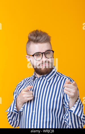 Funny giovane uomo con i baffi e barba e occhiali mostra su di voi su  sfondo giallo. Concetto di non-standard della pubblicità Foto stock - Alamy