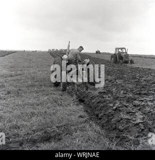 Anni sessanta, storico, un agricoltore sul suo trattore arare un campo in una competizione di aratura, Crediton, Inghilterra, Regno Unito. I punti vengono assegnati per la rettilineità e pulizia del risultante solchi. Foto Stock