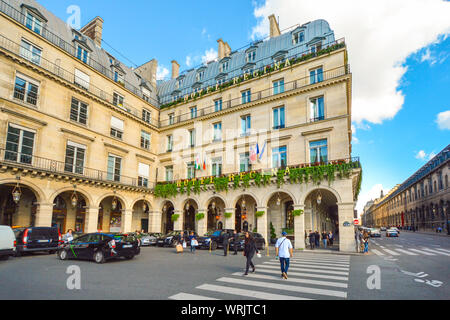 Parco vetture in Place des Pyramides come turisti e pedoni attraversare l'incrocio nella parte anteriore di un albergo di lusso in Rue du Rivoli Foto Stock