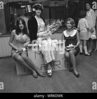 1967, storico, i tre finalisti in un villaggio locale 'Miss adolescente " Concorso di bellezza, con la ragazza vincente in una floreali pantaloni adatti, indossando una corona e tenendo un mazzo di fiori, Inghilterra, Regno Unito. Foto Stock