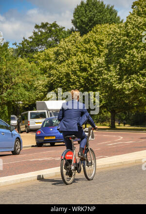 Londra, Inghilterra - Luglio 2018: Persona in una tuta in sella a una moto da una delle city bike noleggio lungo una strada nel centro di Londra. Foto Stock
