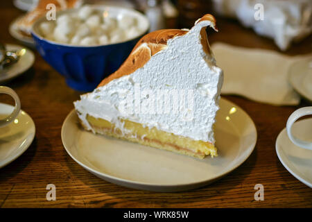 Gigantesco pezzo di yummy Lemon Meringue Pie sul tavolo di legno in una caffetteria. Foto Stock