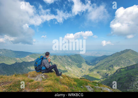 Successo attivo uomo escursionista sulla cima della montagna godendo la vista. Viaggio sport concetto di stile di vita Foto Stock