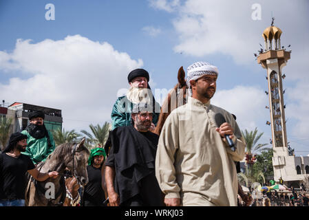 Persone in Jibchit, Nabatiyeh comune, Libano, in lutto per la morte di imam Hussein, nipote del Profeta Maometto, attraverso una rievocazione storica della sua morte durante la battaglia di Karbala in 680annuncio. Un cast di 100 ha preso parte, completa con i cavalli e un cammello. Il Libano, 10 Settembre 2019 Foto Stock