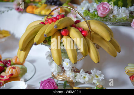 Esso giaceva su piastra di acciaio inossidabile in outdoor .all'interno di banane non cotte e granchio rosso apple di vetro . Pettine di banane che problemi di attualità asia thailandia frutto in giallo Foto Stock